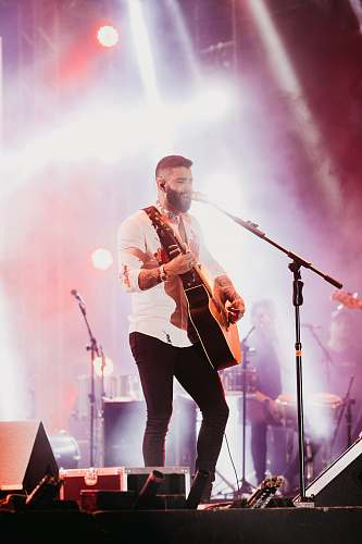 person man playing guitar on stage crowd