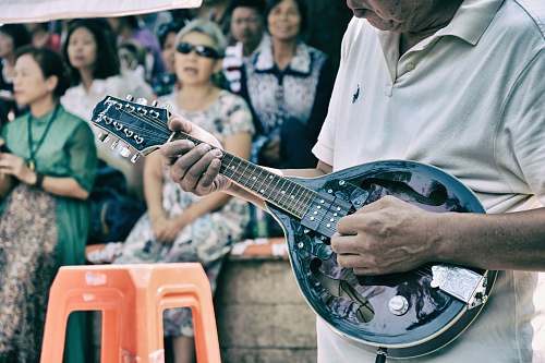 person man playing string instrument near croud people