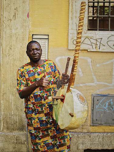 person man playing string instrument near wall people