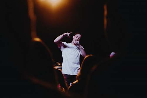 people man raising his left hand while singing person