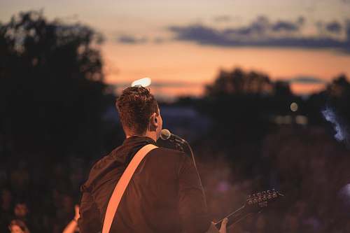 person man signing while playing guitar crowd