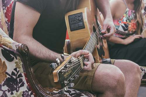person man sitting on chair while playing guitar guitar