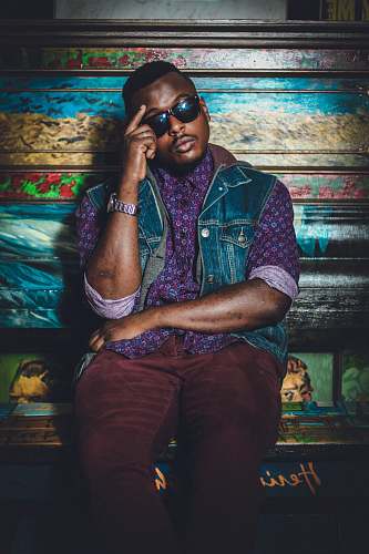 person man sitting wearing sunglasses leaning on floral bench people