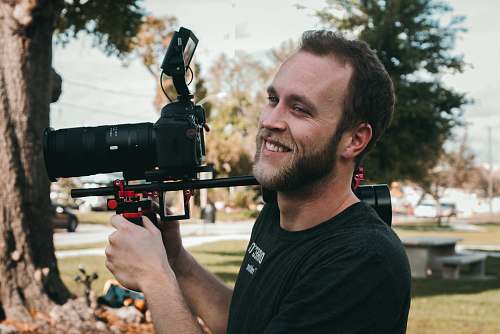 person man smiling standing near the DSLR camera camera