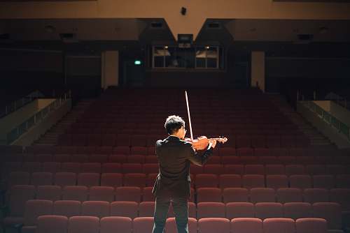 person man standing in front of stage playing violin people