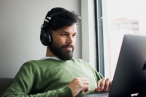 person man wearing headphones while looking at MacBook face