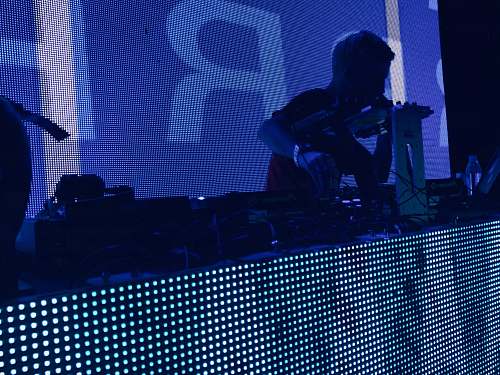 person man wearing t-shirt holding DJ mixer inside dark room people