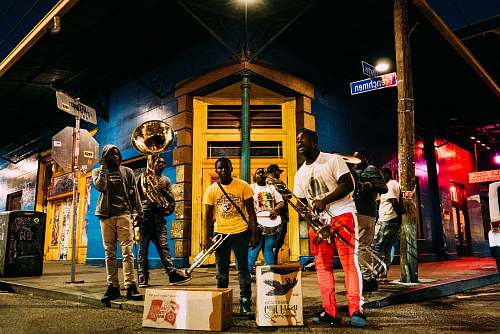 person people holding musical instruments while standing on street during nighttime people