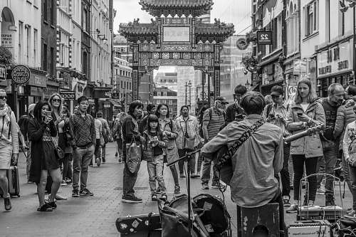 person people watching man playing guitar in the street black-and-white