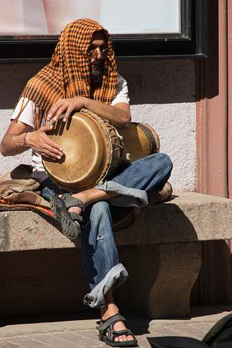 person person in blue denim jeans sitting on brown concrete bench musical instrument