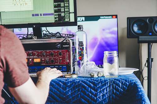 person person using computer beside clear glass bottle and jar on blue tablecloth people