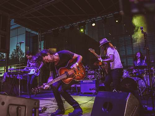 person photography of man playing guitar near stage guitar