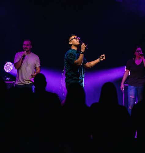person selective focus photography of three people performing on stage stage