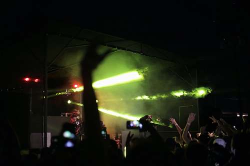 person silhouette of crowd raising hands fronting concert stage people