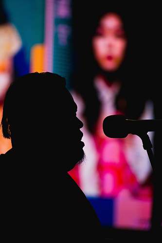 audience silhouette photography of man in front of a microphone crowd