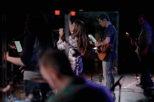 person woman holding microphone singing beside man playing guitar people