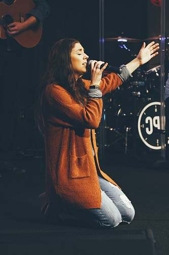 person woman kneeling while holding microphone apparel