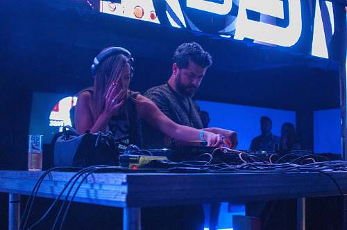 people woman playing DJ controller beside man in gray shirt person