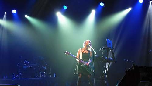 person woman playing guitar on stage people