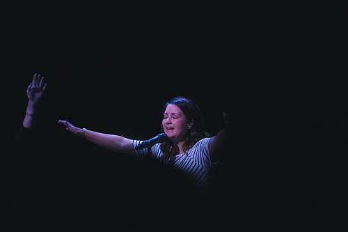 person woman singing on stage raising her hands performer