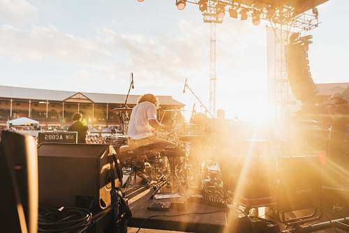 orange photo of music band performing at front of crowded stadium under blue sky artist