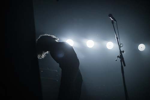flare person standing beside microphone stand light
