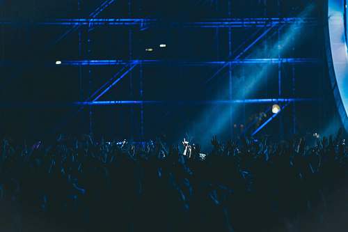 blue group of people raising hands inside building live