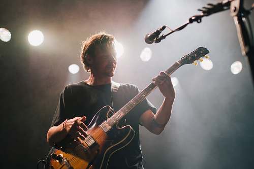 person man playing guitar under spotlight performer