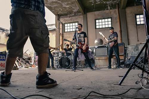 guitar man singing with band mates on gray concrete room human