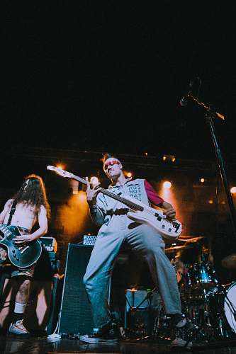 person man standing on stage playing electric bass guitar guitar
