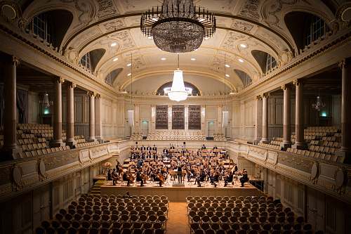 ballroom music group performing on stage with empty audience seats indoors