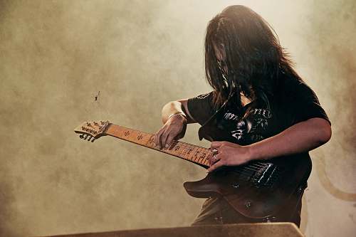 human person holding black electric guitar guitar