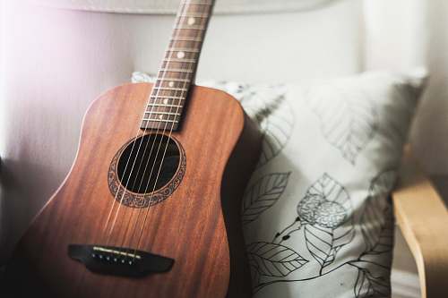 guitar selective focus photo of brown guitar on white pillow leisure activities