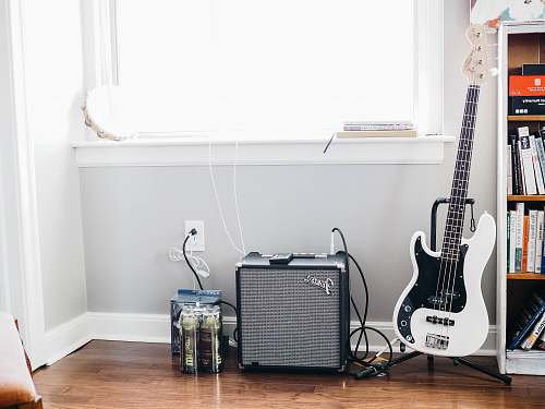 guitar white and black stratocaster guitar on black guitar stand beside black Fender guitar amplifier electric guitar