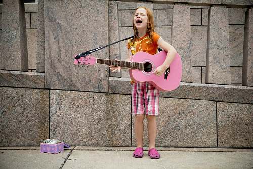 human girl playing guitar near wall person