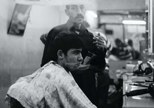 person grayscale photo of man inside barber shop black-and-white
