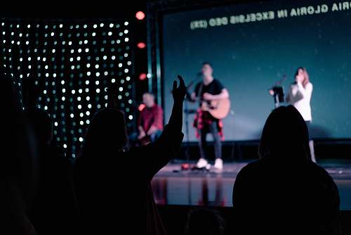 person man and woman on stage with people praising human