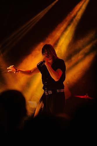 human man holding microphone standing on stage with lightings person