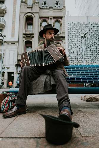 human man sitting on bench playing accordion music
