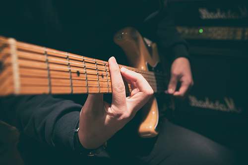 human person wearing black shirt paying guitar in closeup photography person