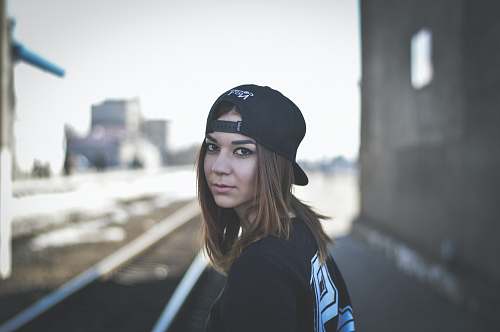 human woman wearing black snapback cap looking back person