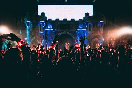 music crowded people wearing LED bracelet raising hands in front of stage leisure activities