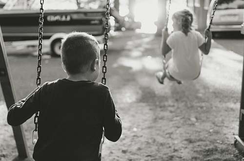 swing grayscale photography of boy and girl on swing toy