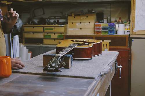 human guitar resting on table near person in the kitchen wood