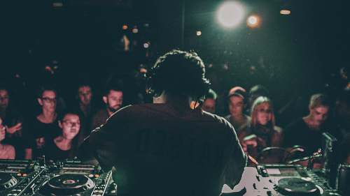 human man in grey shirt operating black DJ turntable inside room people