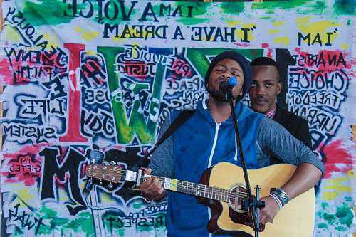 human man playing acoustic guitar while singing people
