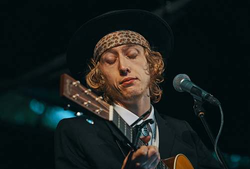 human man playing brown guitar people