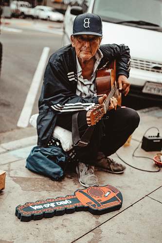 human man playing guitar while sitting people