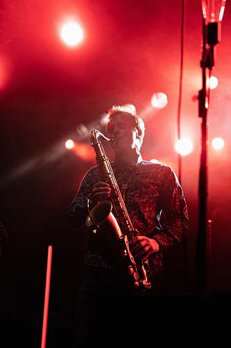 human man playing saxophone on stage crowd