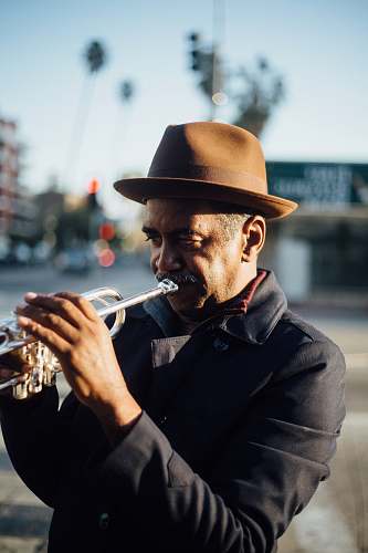 human man playing trumpet during daytime people